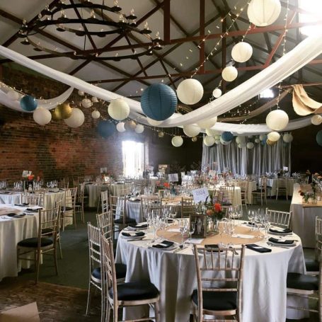 Elegant reception venue with tables, white tablecloths, and decorative lanterns.